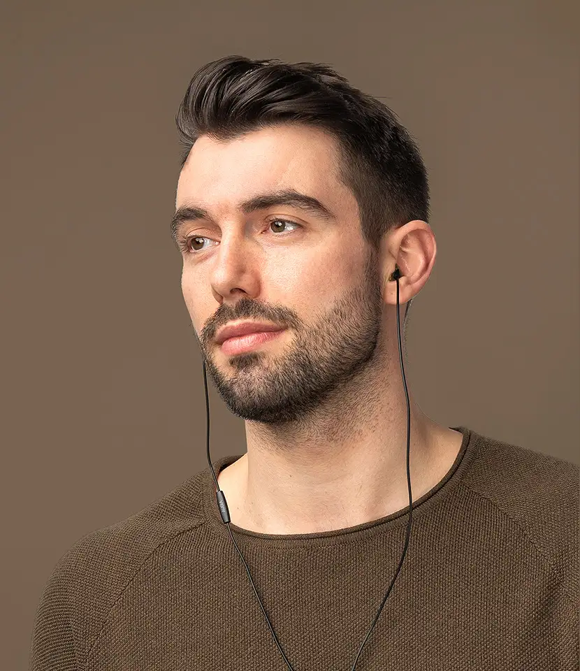 Männliches Model mit Kopfhörern im Ohr.